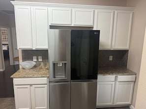 A stainless steel refrigerator with a water dispenser, white cabinetry, and granite countertops in a kitchen. - Awesome 3-bedroom house with AC in quaint Denham Springs (Denham Springs)