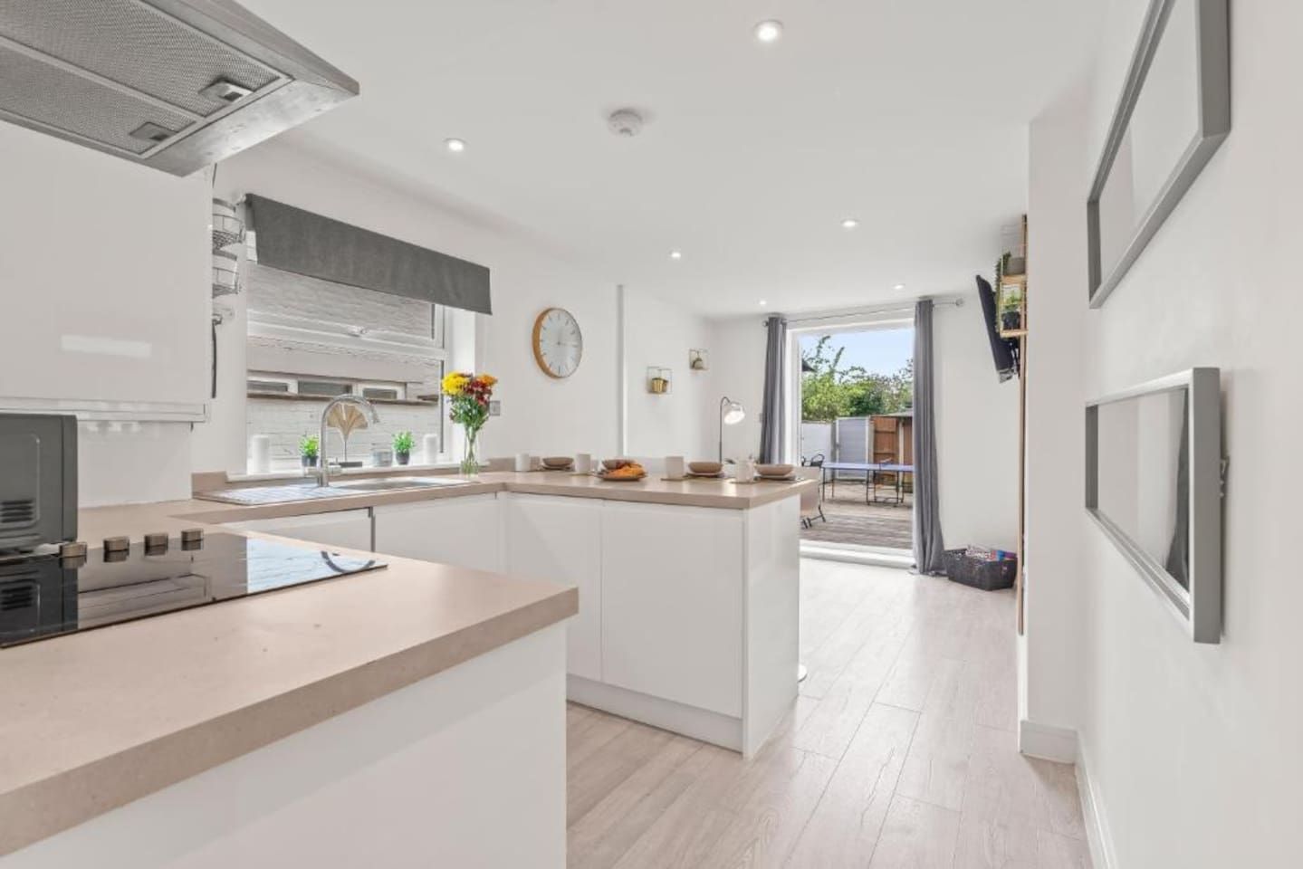 A modern kitchen with a central island, a dining area, and a view of the outdoors.