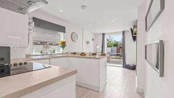 A modern kitchen with a central island, a dining area, and a view of the outdoors.