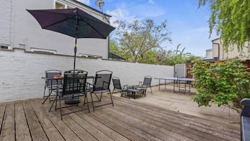 An outdoor patio with a table and chairs, a ping pong table, and a satellite dish on a white building.