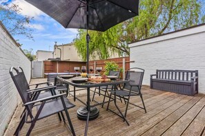 Une terrasse extérieure avec une table et des chaises, un barbecue et une plateforme en bois.