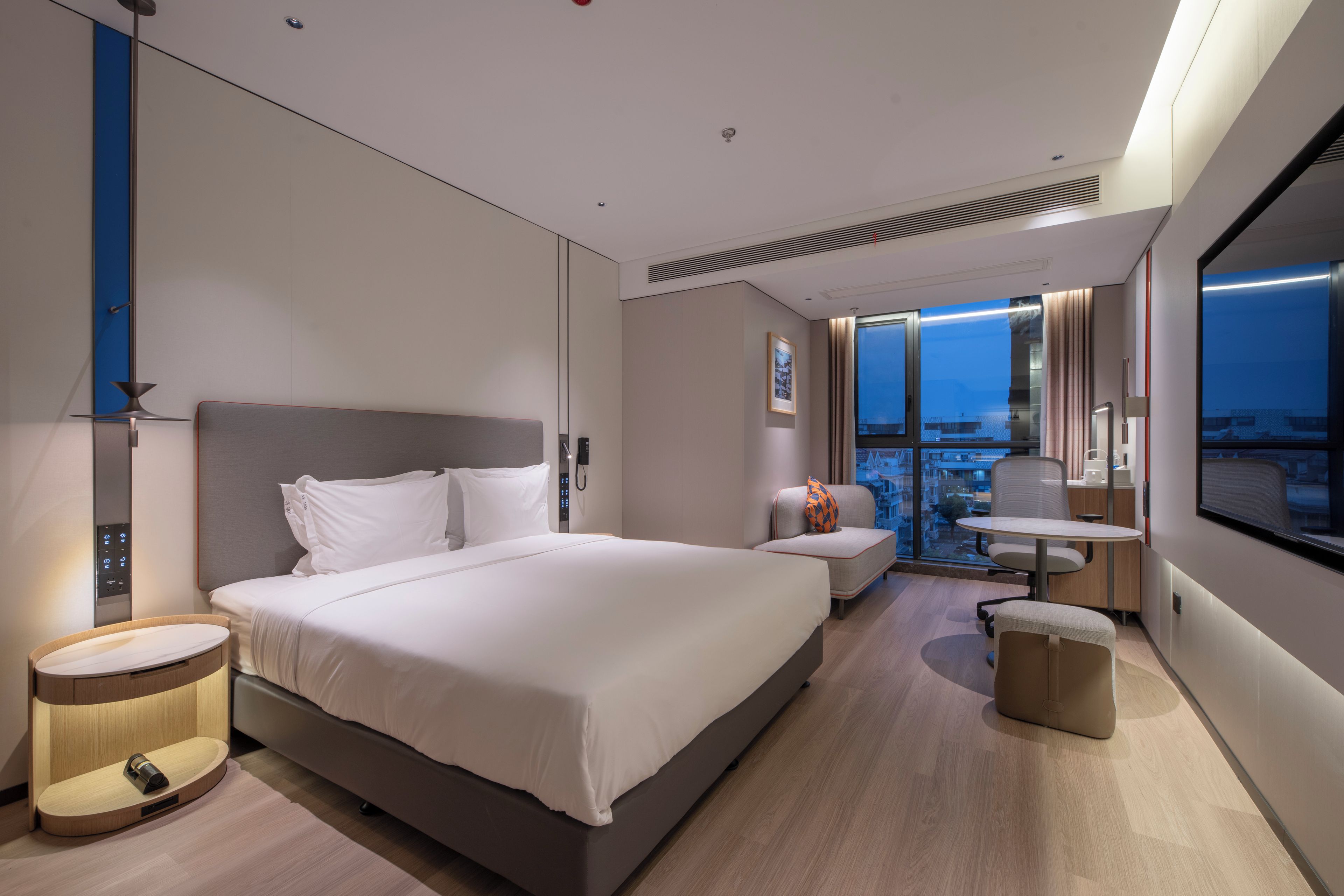 Una habitación de hotel moderna con una cama grande, un escritorio y vistas a la ciudad.