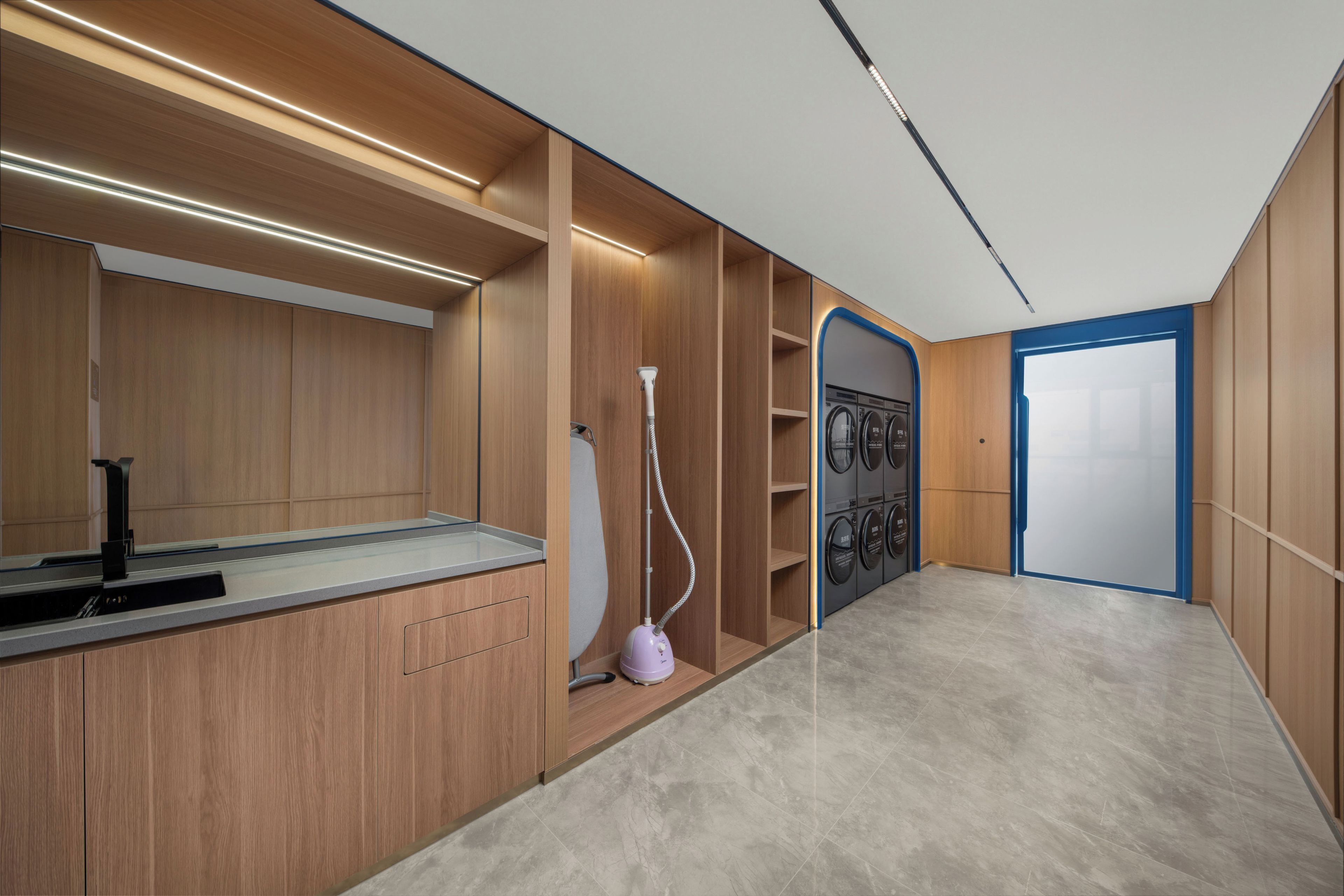 Een moderne badkamer met een houten wastafelmeubel, een spiegel, een wastafel, een handdouche en een wandmodel wasmachine.