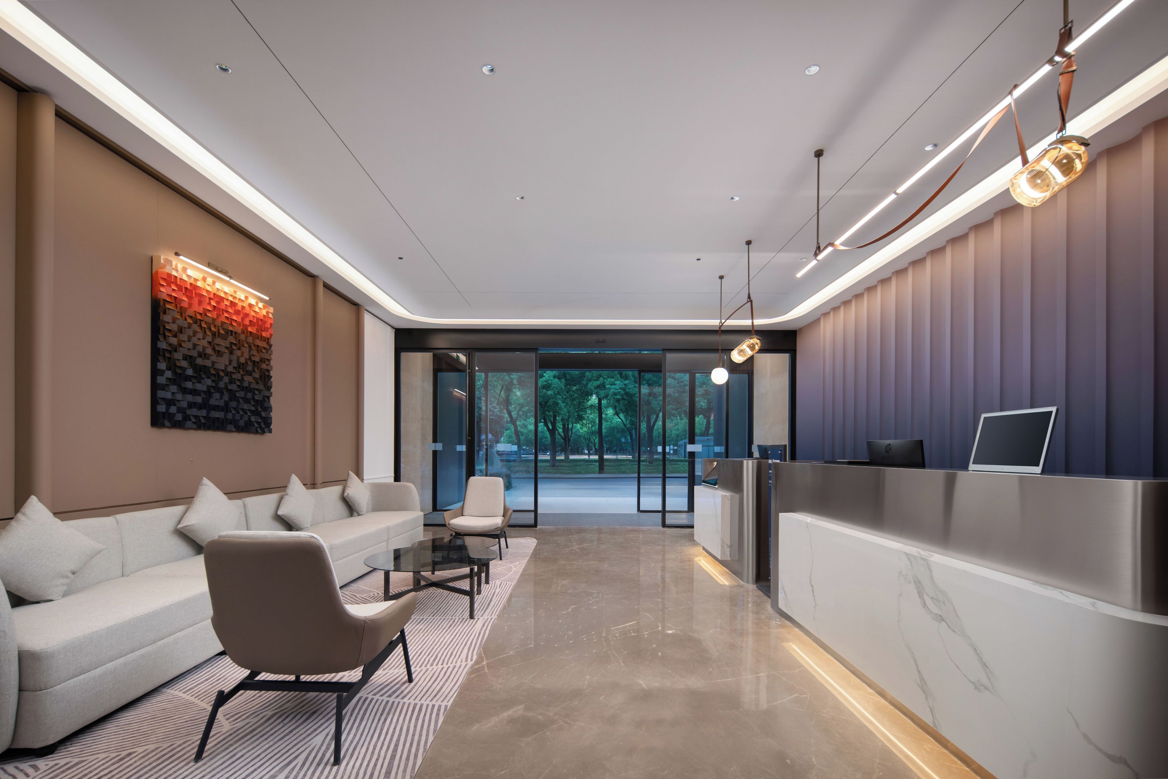 A modern lobby with a reception desk, seating area, and large windows.