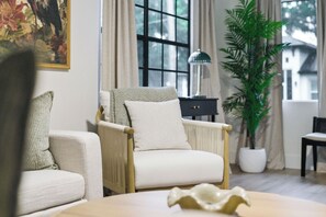 Een woonkamer met een bank, fauteuil en een potplant.
