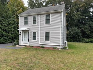 A two-story house with a front porch, a garage, and a lawn. - Cozy house on one acre land with great privacy. 20 miles away from Boston (Framingham)