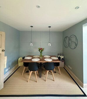 Ein Esszimmer mit einem Holztisch, vier Stühlen, zwei Pendelleuchten und einer Blumenvase.