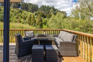 Eine Terrassenausstattung mit Korbmöbeln und einem Tisch mit Glasplatte.