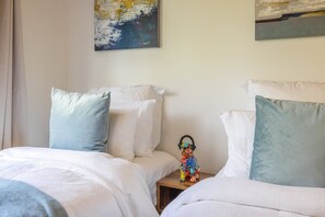 A bedroom with two beds, each with a pillow and a small table with a decorative item. - The Tasting Room by Waiheke Pure, close to wineries, great valley views (Auckland)