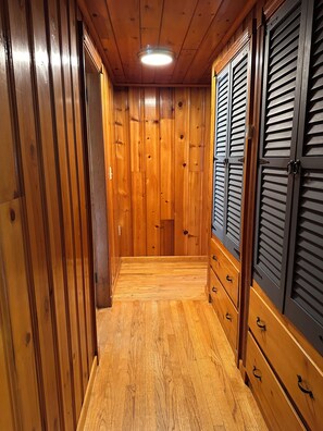 A hallway with wooden walls and a wooden floor, leading to a room with a door. - Lakefront Maine Getaway - Private Dock & Kayaks (Burnham)