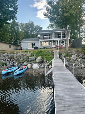 Une propriété située au bord de l’eau, dotée d’un quai, de kayaks et d’une maison avec balcon.