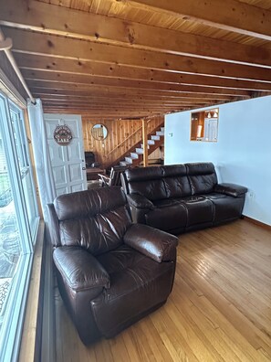Et interiør i træ med en lædersofa, en trappe og udsigt gennem et vindue.
