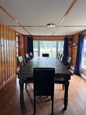 A conference room with a long table, chairs, and a view through large windows. - Lakefront Maine Getaway - Private Dock & Kayaks (Burnham)