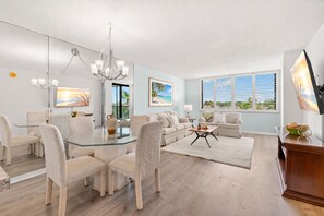 A modern living room with a glass dining table surrounded by chairs, a sofa, and a coffee table. - Endless Summer! Salty vibes only. (St. Petersburg)