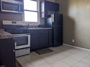Una cocina equipada con estufa, horno, microondas, fregadero y un refrigerador negro.
