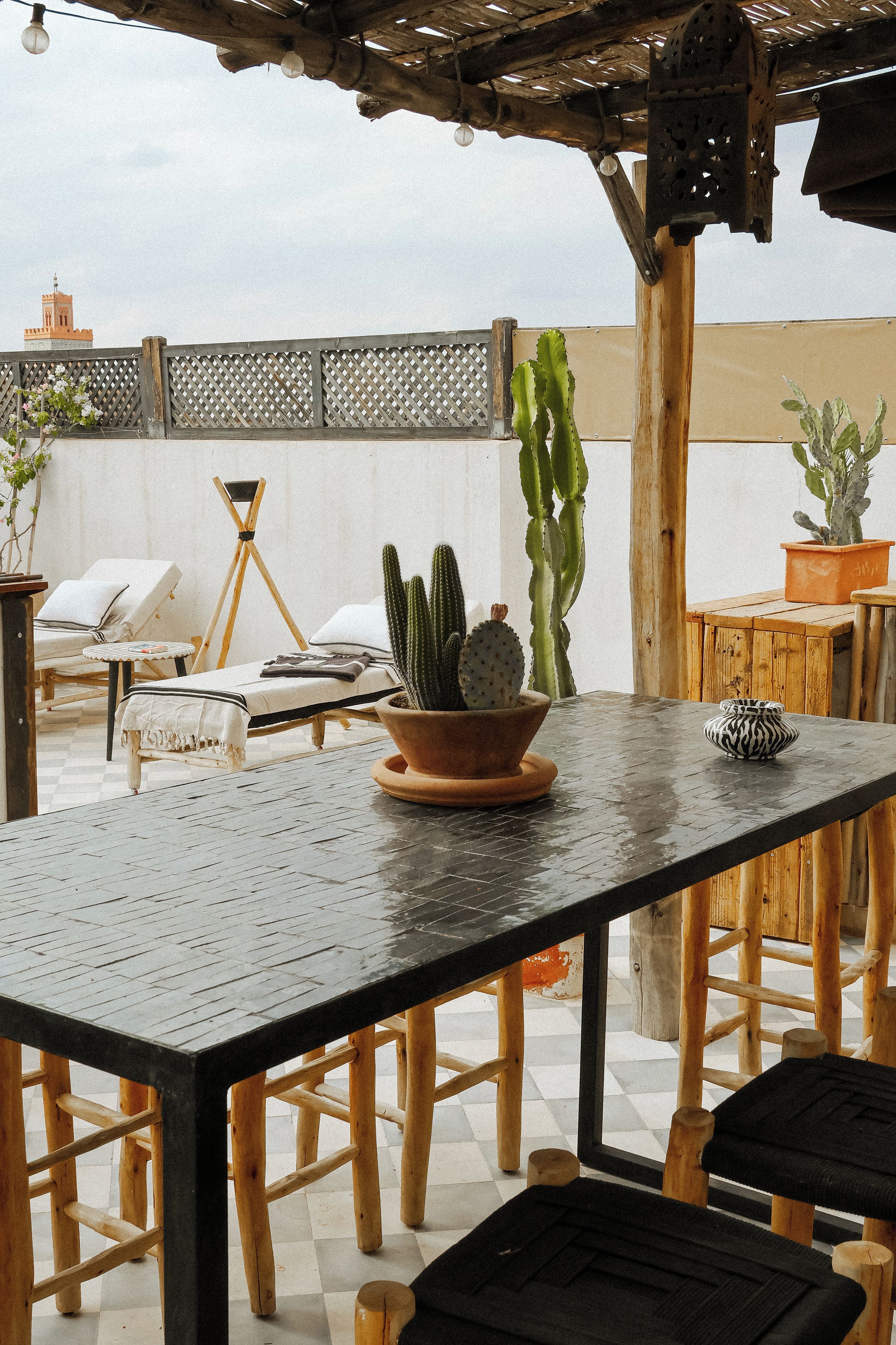 An outdoor patio with a table, chairs, and potted plants.