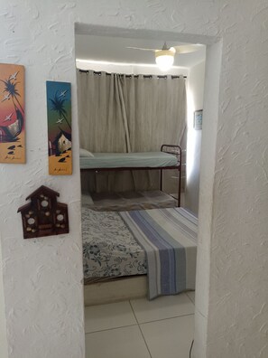A room with a bunk bed, a ceiling fan, and a wall-mounted birdhouse. - Apartamento na Barra (Salvador)