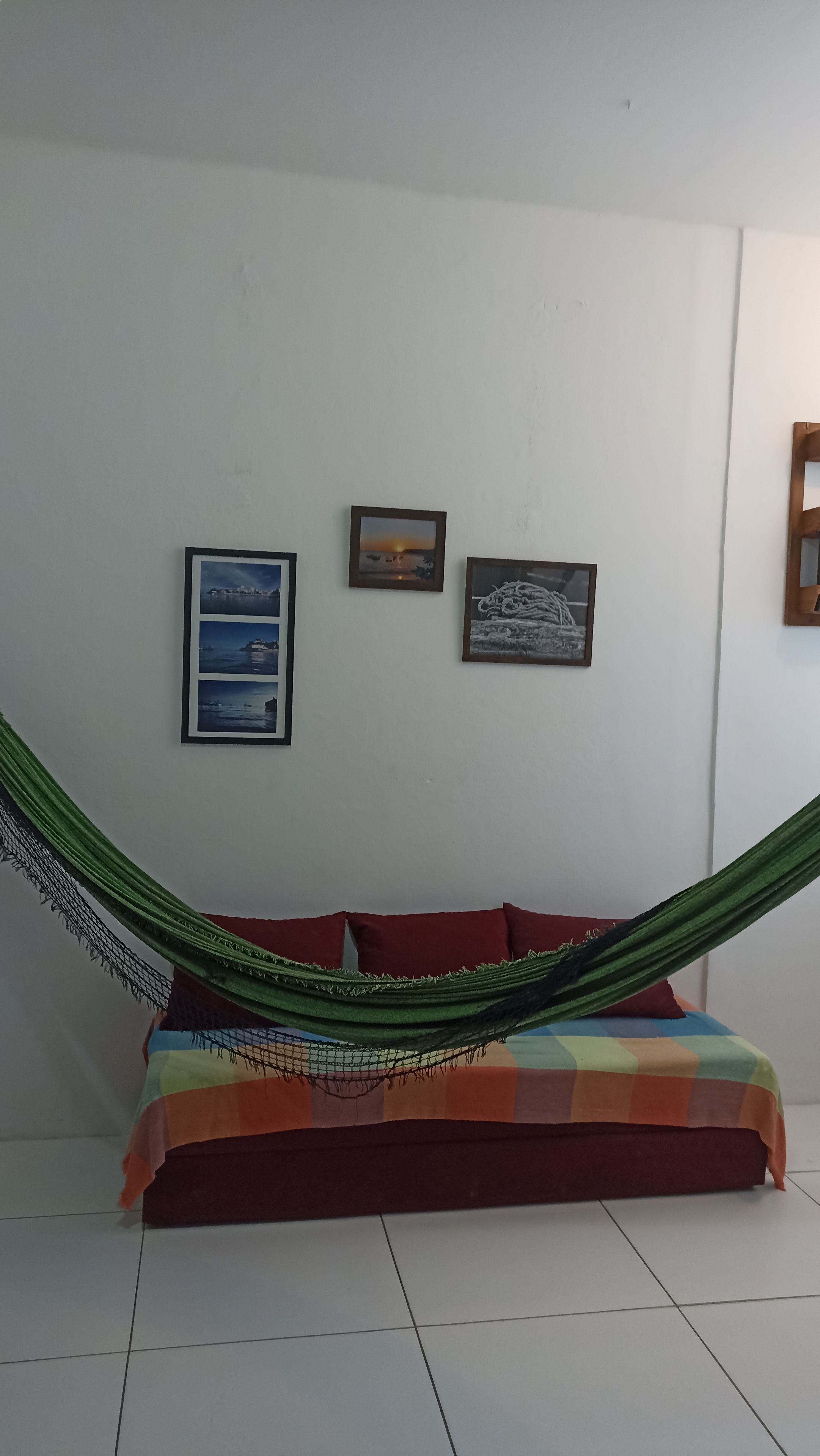 Una habitación con una hamaca, un sofá y tres cuadros en la pared.