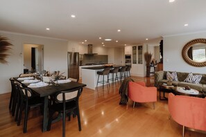Una cocina moderna con una isla central, comedor con mesa de madera oscura y zona de estar con sofá y sillones.
