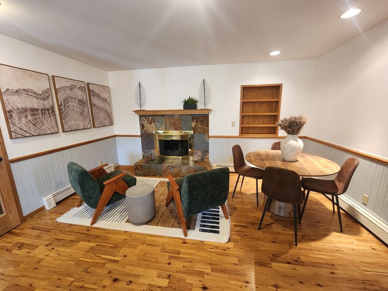 Una sala de estar acogedora con chimenea, un comedor con mesa y sillas redondas, y obras de arte en las paredes.