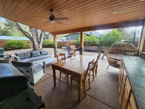 Un patio al aire libre con una mesa y sillas de madera, un sofá y una silla colgante.