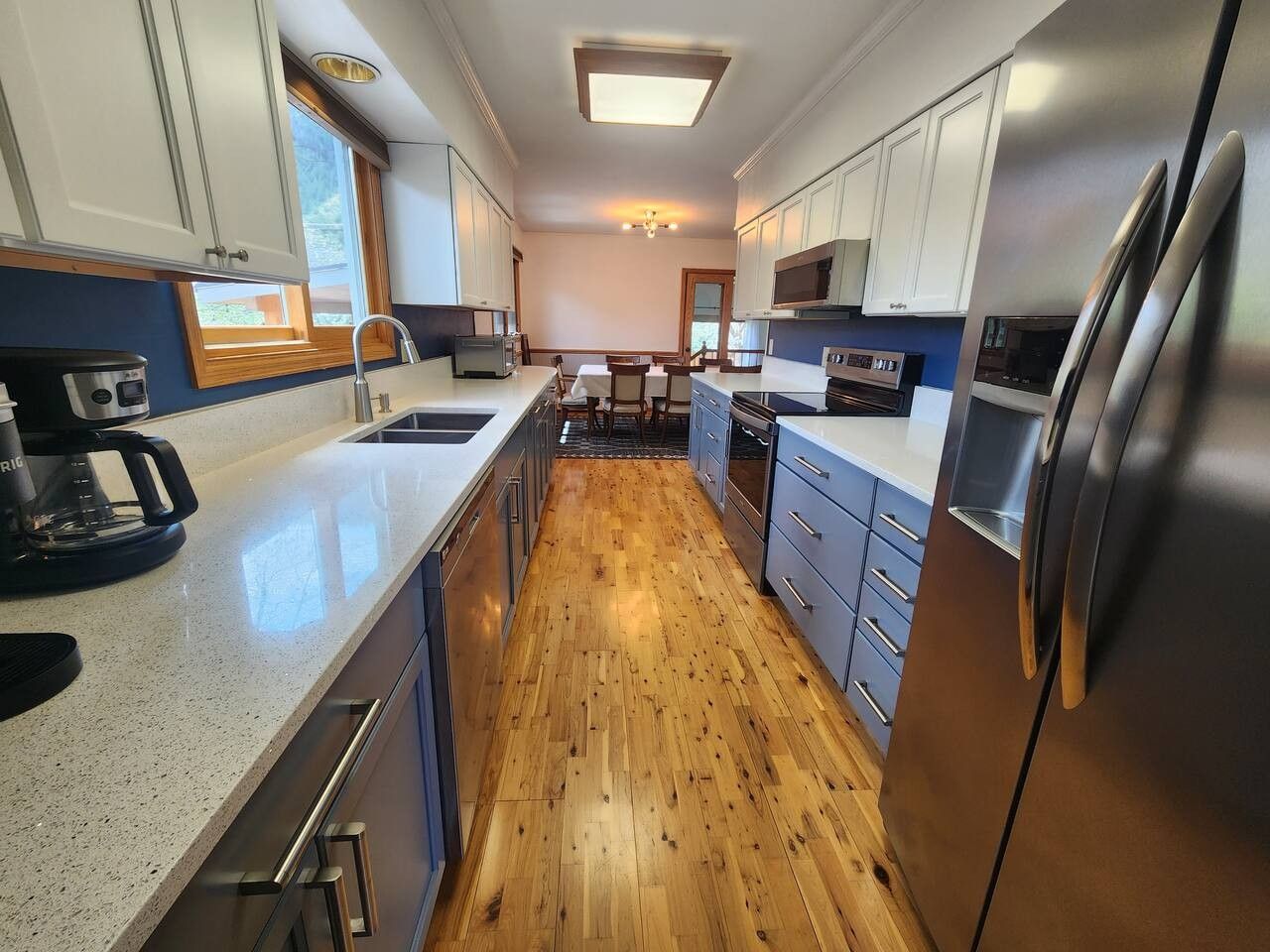 Una cocina moderna con electrodomésticos de acero inoxidable, piso de madera y una isla central.