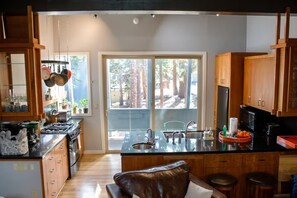 A modern kitchen with a central island, wooden cabinets, and a view of the outdoors. - 2BD/2BA Condo Near Bike Path/Shuttle Stop/Village/Lodges (Mammoth Lakes)