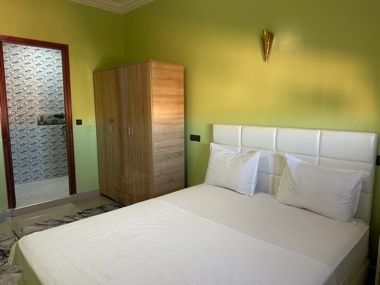 A bedroom with a bed, a wardrobe, and a mirror.