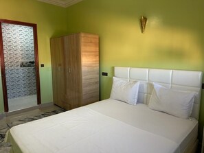A bedroom with a bed, a wardrobe, and a mirror.