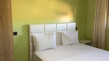 Ein Hotelzimmer mit einem großen Bett, einer Holztür und einer hellgrünen Wand.