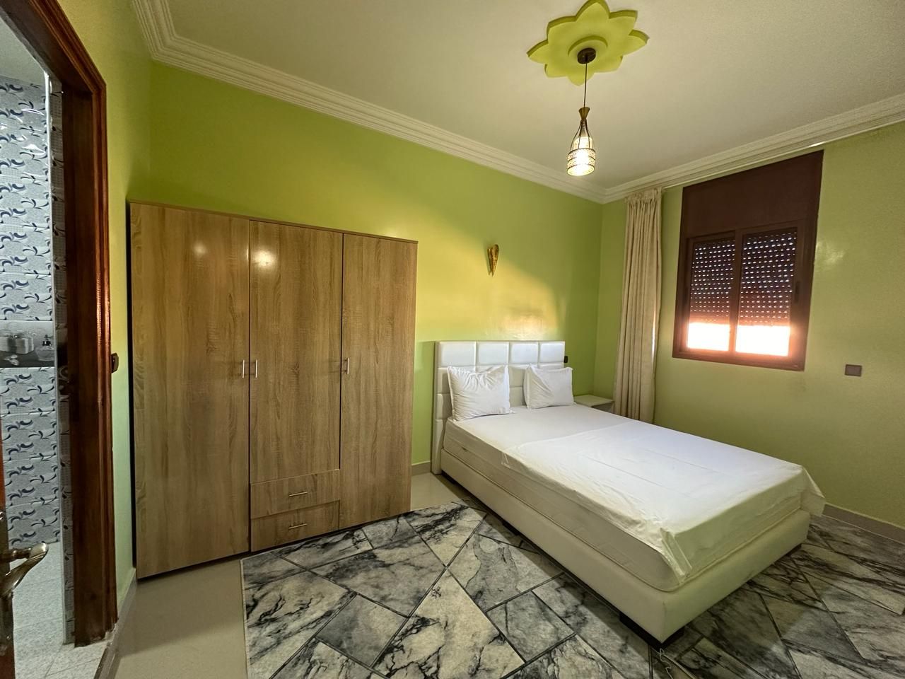 Un dormitorio con cama, armario y ventana con persianas.