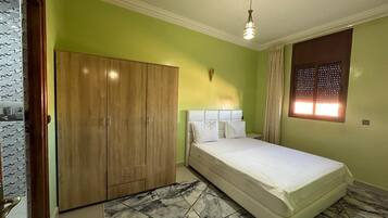 Un dormitorio con cama, armario y ventana con persianas.