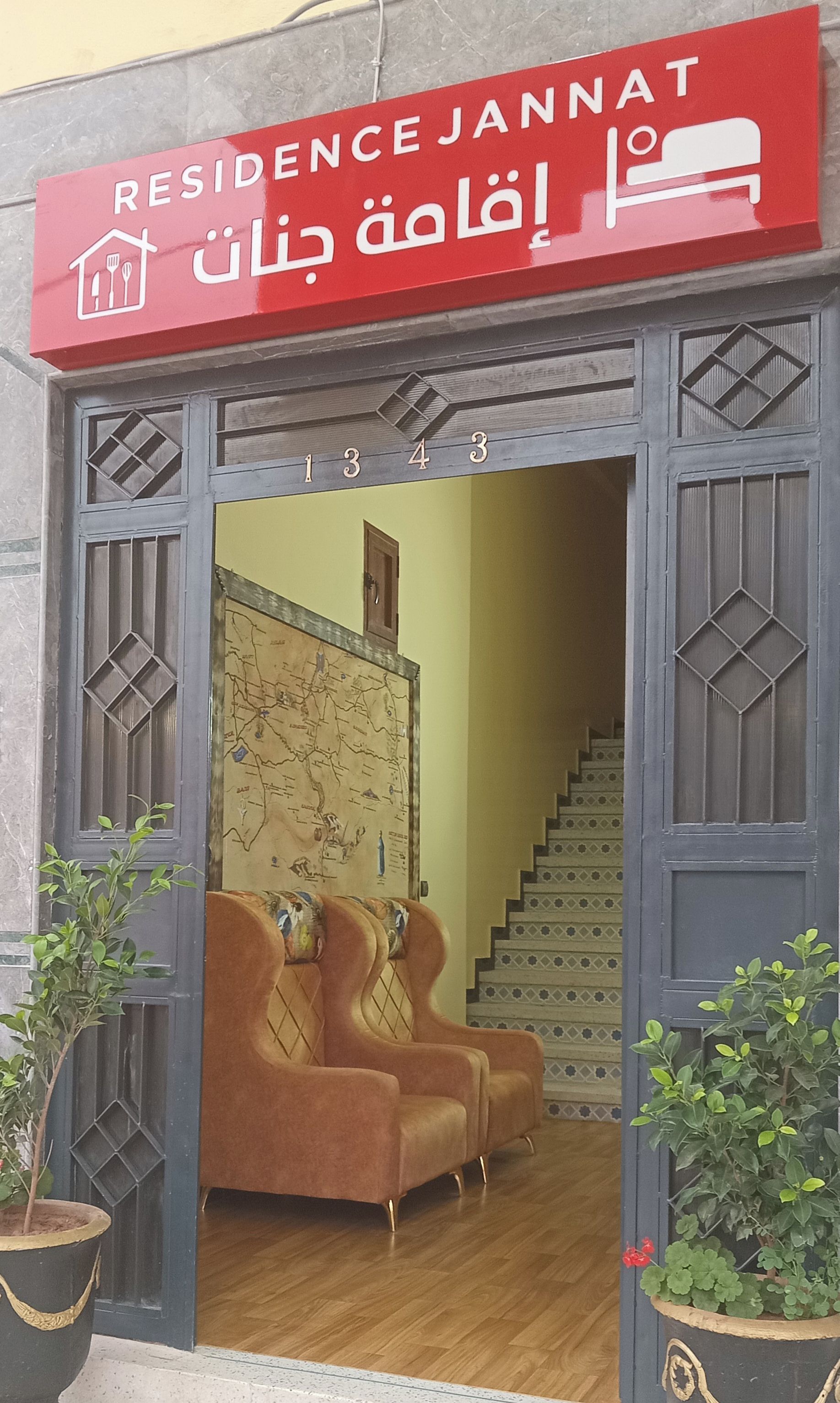 L’entrée de la résidence est signalée par une enseigne rouge indiquant « Résidence Jannat » et un numéro, « 1343 », placé au-dessus de la porte.