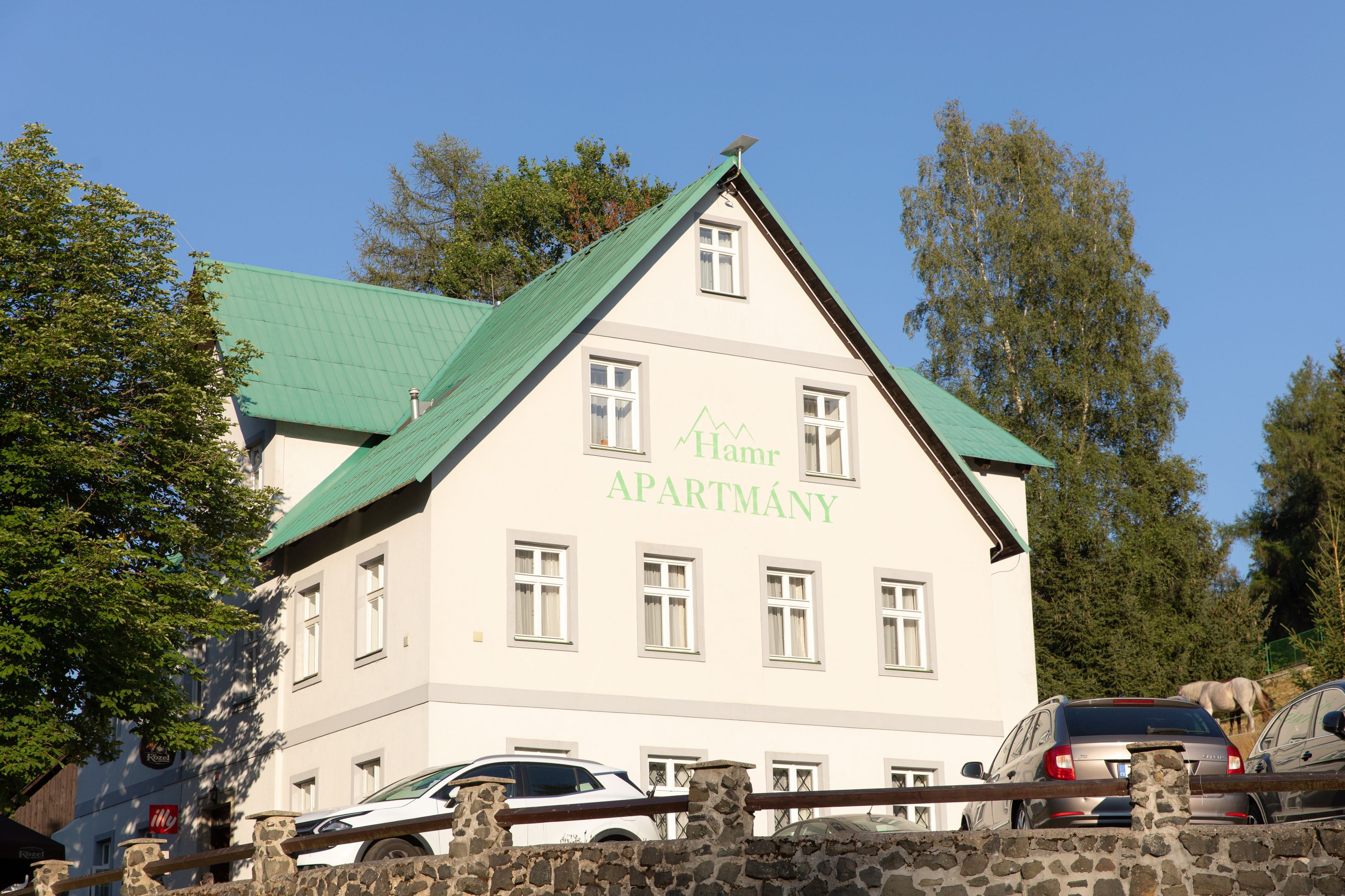 Kaksikerroksinen rakennus, jossa on vihreä katto ja useita ikkunoita.