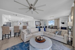 A modern living room with a sectional sofa, a round coffee table, and a ceiling fan. - Gulf Coast Beach Oasis Getaway (Gulf Shores)