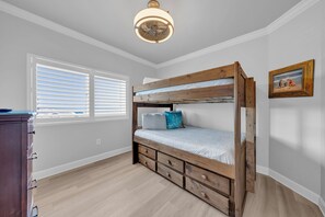 A bunk bed with a wooden frame, a white mattress, and a blue pillow. There is a dresser with multiple drawers and a ceiling fan. - Gulf Coast Beach Oasis Getaway (Gulf Shores)