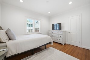 A bedroom with a bed, a dresser, a television on top of the dresser, and a window with blinds. - Modern Fully Furnished House - 3 Bed 2 Bath King Bed Pool & Jacuzzi (San Jose)