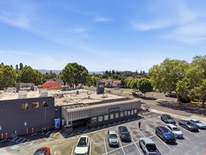 Een parkeerplaats met meerdere auto's, een gebouw met een gestreepte luifel en een helderblauwe lucht.