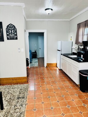 A kitchen with white cabinets, a black countertop, and a tiled floor. - Charming 1-bedroom cottage in Ruston located perfectly for your convenience (Ruston)