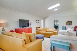 A modern living room with a flat-screen TV, a red dresser, and a yellow sofa. - Spacious Tucson Retreat, Near UofA & Banner, Private Yard & Fire Pit (Tucson)