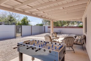 Ein Terrassenbereich im Freien mit Kicker, Sitzgelegenheiten und einer überdachten Terrasse.