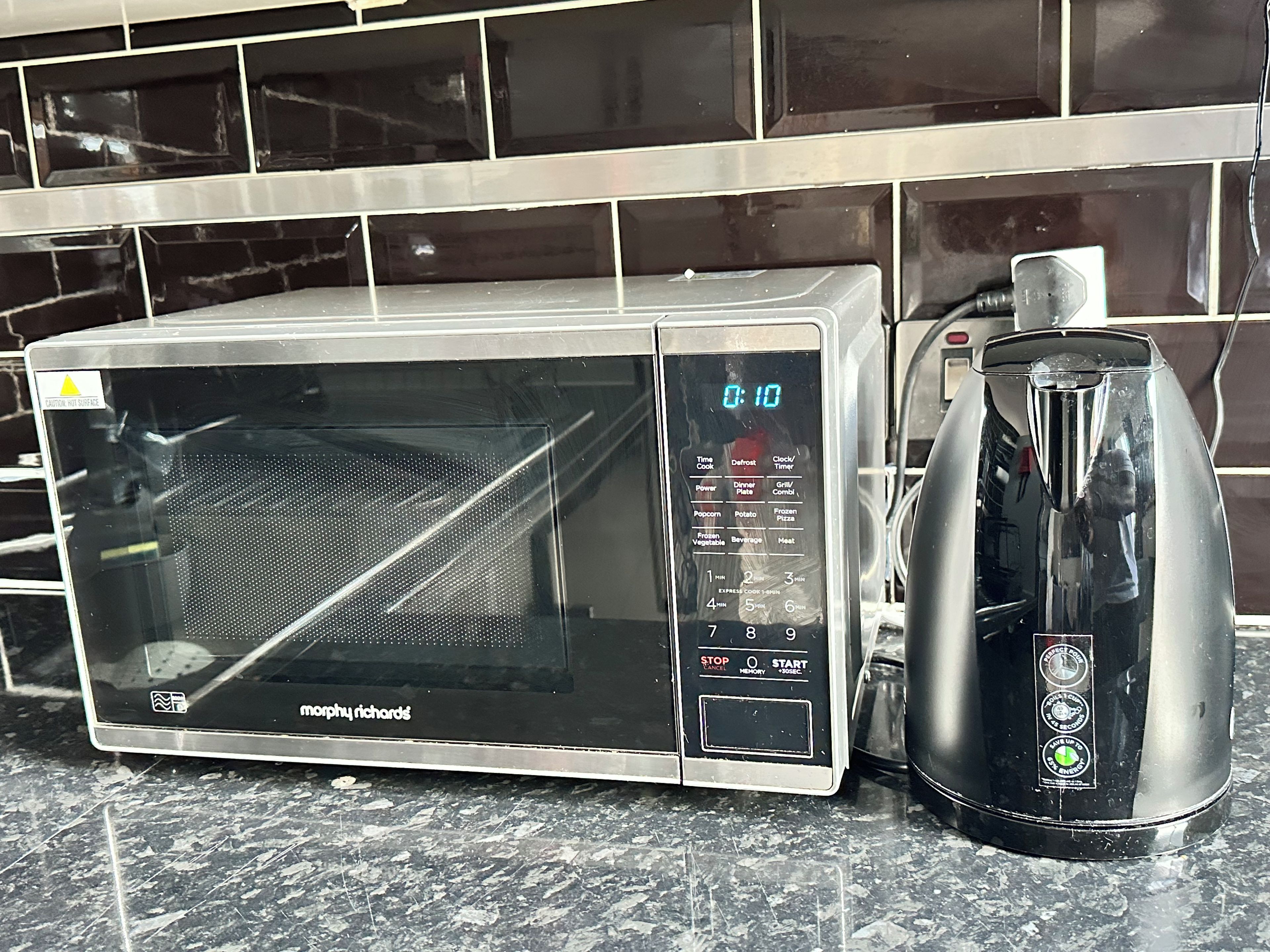 A microwave oven with a digital display and a coffee maker on a kitchen counter.