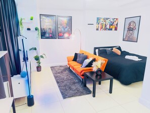 A modern living room with a sofa, a bed, and artwork on the walls. - Smart Artistic 1-bedroom studio in Shoreditch London with stunning city views (London)