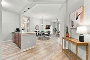 A modern kitchen with a central island, dining area with a table and chairs, and a living space with a sofa and a TV. - 3BR at Vista Cay, Where Comfort Meets Convenience (Orlando)
