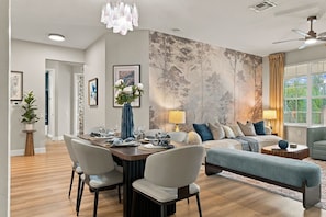 Een moderne woonkamer met een eethoek, een zithoek en een groot muurschilderij.