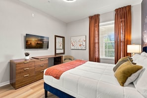 Een slaapkamer met een bed, een dresser, een spiegel en kunstwerken aan de muur.