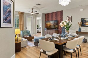 A modern dining area with a wooden table set for four, surrounded by chairs. - Luxury 3br, Modern Design, Lake Views, Vista Cay (Orlando)