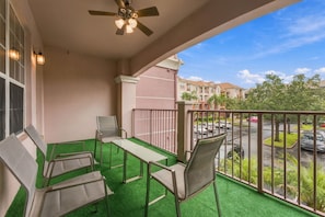 Ein Balkon mit Deckenventilator, Tisch und Stühlen.