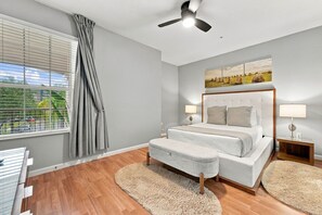 Ein Schlafzimmer mit einem Bett, Nachttischen, einem Deckenventilator und einem Fenster mit Vorhängen.