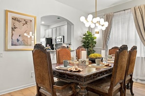 A dining room with a large wooden table, ornate chairs, and a chandelier. - 6BR Near Disney, Pool, Games and Themed Rooms (Kissimmee)